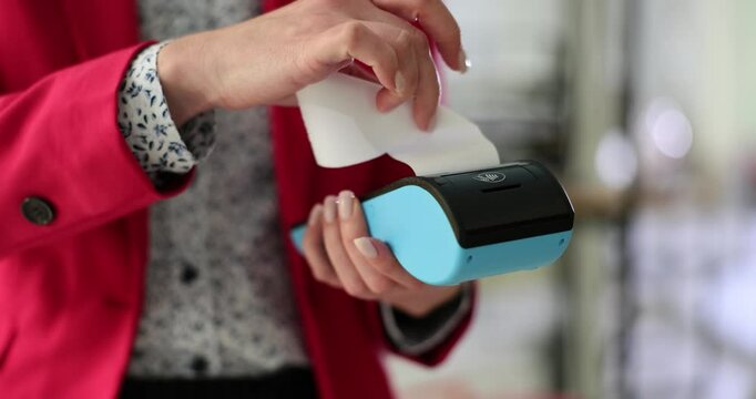 Woman holds POS and picks up check from wireless payment terminal in hands. Digital technology in banking service in modern office slow motion
