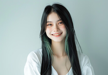 Photo of Asian girl straight hair smiling wearing white attire She green highlight her long black hair positioned against clean background focus should upper body highlight facial expression detail of