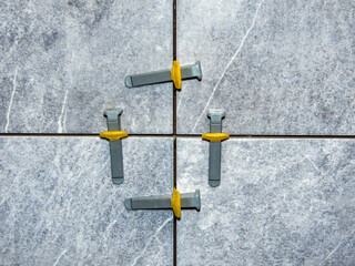 tile leveling system , laying gray marble effect porcelain tiles on the wall