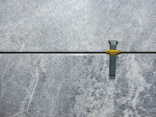 wedge and clamp in tile leveling system , laying gray marble effect porcelain tiles on the wall