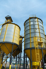 silver silos on agro manufacturing plant for processing drying cleaning and storage of agricultural products, flour, cereals and grain. Large iron barrels of grain. Granary elevator