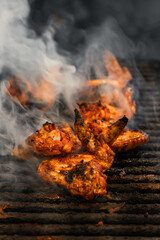 Juicy chicken wings cooking on a smoky barbecue, exuding a mouth-watering aroma.
