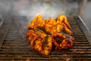 Juicy chicken wings cooking on a smoky barbecue, exuding a mouth-watering aroma.