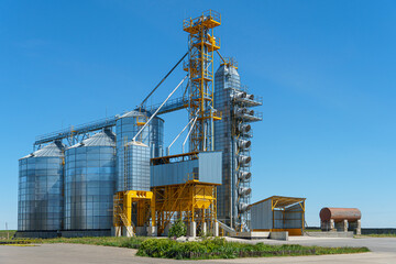 silver silos on agro manufacturing plant for processing drying cleaning and storage of agricultural products, flour, cereals and grain. Large iron barrels of grain. Granary elevator