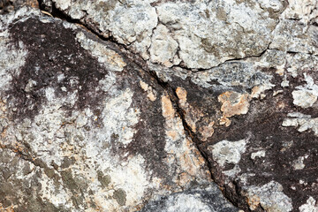 A close-up image of cracked rock. Rugged surface of fractured texture background.