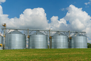 silver silos on agro manufacturing plant for processing drying cleaning and storage of agricultural products, flour, cereals and grain. Large iron barrels of grain. Granary elevator