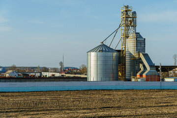 silver silos on agro manufacturing plant for processing drying cleaning and storage of agricultural products, flour, cereals and grain. Large iron barrels of grain. Granary elevator