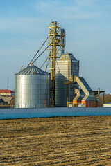 silver silos on agro manufacturing plant for processing drying cleaning and storage of agricultural products, flour, cereals and grain. Large iron barrels of grain. Granary elevator