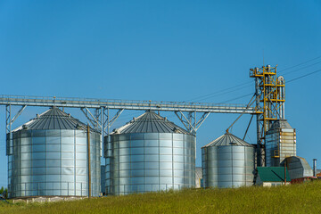 silver silos on agro manufacturing plant for processing drying cleaning and storage of agricultural products, flour, cereals and grain. Large iron barrels of grain. Granary elevator