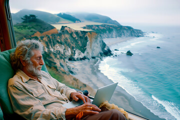 An elderly man with grey hair and a beard is sitting comfortably in a train, using a laptop.