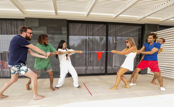 Friends playing tug-of-war at a summer house party