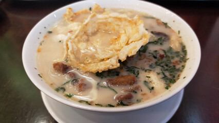 Traditional Indonesian Soto Betawi Soup with Creamy White Broth and Crispy Toppings in a Restaurant Setting