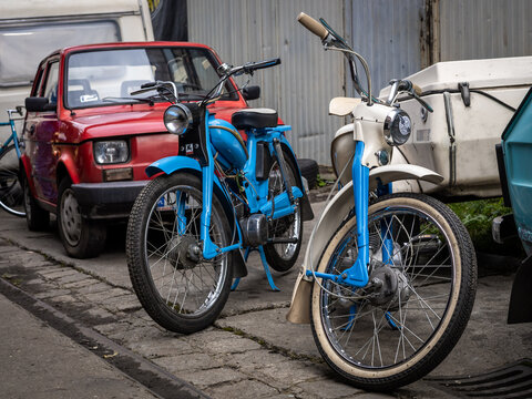 Wroclaw, Poland - September 19, 2021:
Two vintage blue Komar motorcycles and a red 126 Fiat car parked in Popowice depot. 