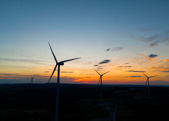 Obraz premium wind turbine in the countryside in the time of sunset background. Wind Turbines at Sunset. Aerial view of a wind farm at sunset.