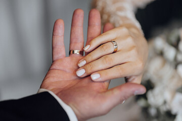 A couple is holding hands and wearing wedding rings. The man's ring is on the woman's finger