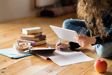 Female student sitting on floor, reading books, studying for final exam at university. Productive...