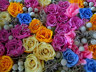 Colorful artificial vivid roses background pattern. Decoration white, purple, pink, violet, orange,...