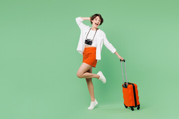 Full body traveler smiling happy woman wears casual clothes hold suitcase bag posing look camera...