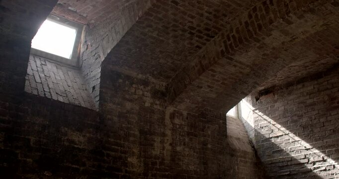Sunlight shining through small windows in a damp basement. Natural light or a view, adding to the feeling of confinement. Windows found high on the walls of a basement. 