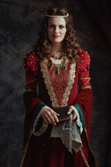 medieval queen in red dress with book and handkerchief