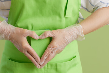 Modern woman showing heart hands isolated on green