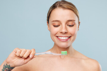 Beautiful smiling cheerful happy half naked topless young woman with nude make up brushing teeth...