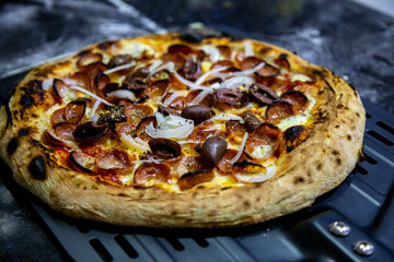 Calabrian sausage pizza served on a round board and set table