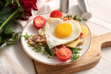 Plate with tasty fried egg, toast, tomatoes and arugula on light wooden background, closeup