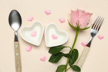 Beautiful table setting with hearts and pink rose on beige background. Valentine's Day celebration