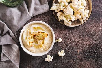 Homemade creamy cauliflower soup in a bowl on the table top view
