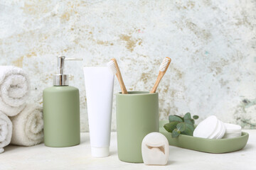 Set of bath supplies with toothbrushes and floss on light background