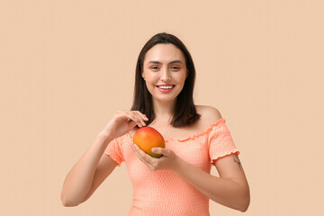 Beautiful young woman with sweet mango on beige background