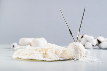A ball of thread, hooks and an uncrocheted knitting on a blue table