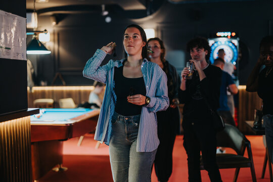 A group of friends enjoys a joyful evening together, playing darts and socializing in a cozy bar atmosphere.