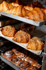 Close-up of freshly baked bread and croissants displayed on a rack in a bakery. Variety of baked goods