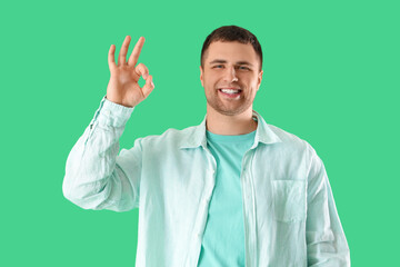 Handsome man showing OK on green background