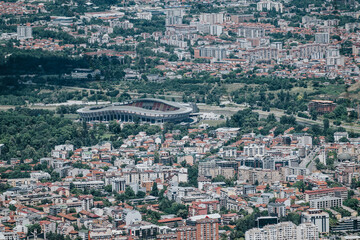 A captivating aerial view of a bustling city, featuring a modern stadium surrounded by residential buildings and lush greenery.