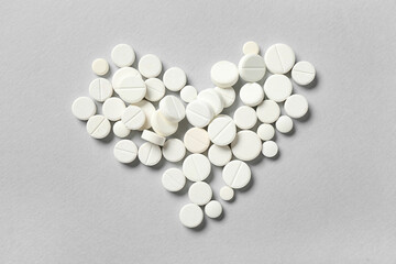 Heart made of white pills on grey background