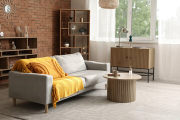 Obraz premium Interior of cozy living room with grey sofa, table and drawers