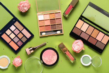 Makeup products with roses and confetti on green background