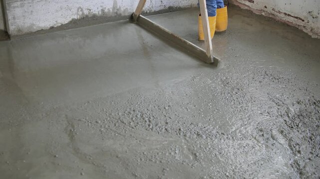 Cement mortar. Leveling fresh concrete with a long leveler. Liquid cement mortar is poured into the formwork