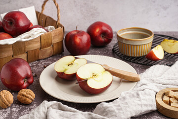 Plate and basket with fresh red apples on dark table