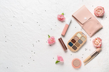 Case for brushes with makeup products, flowers and sequins on white grunge background