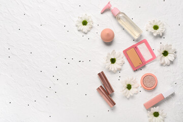 Makeup products with daisies and sequins on white grunge background