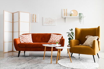 Interior of light living room with sofa, armchair and folding screen
