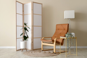 Interior of stylish living room with armchair, lamp and folding screen