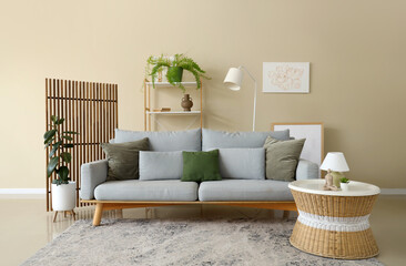 Interior of living room with grey sofa, table and wooden folding screen