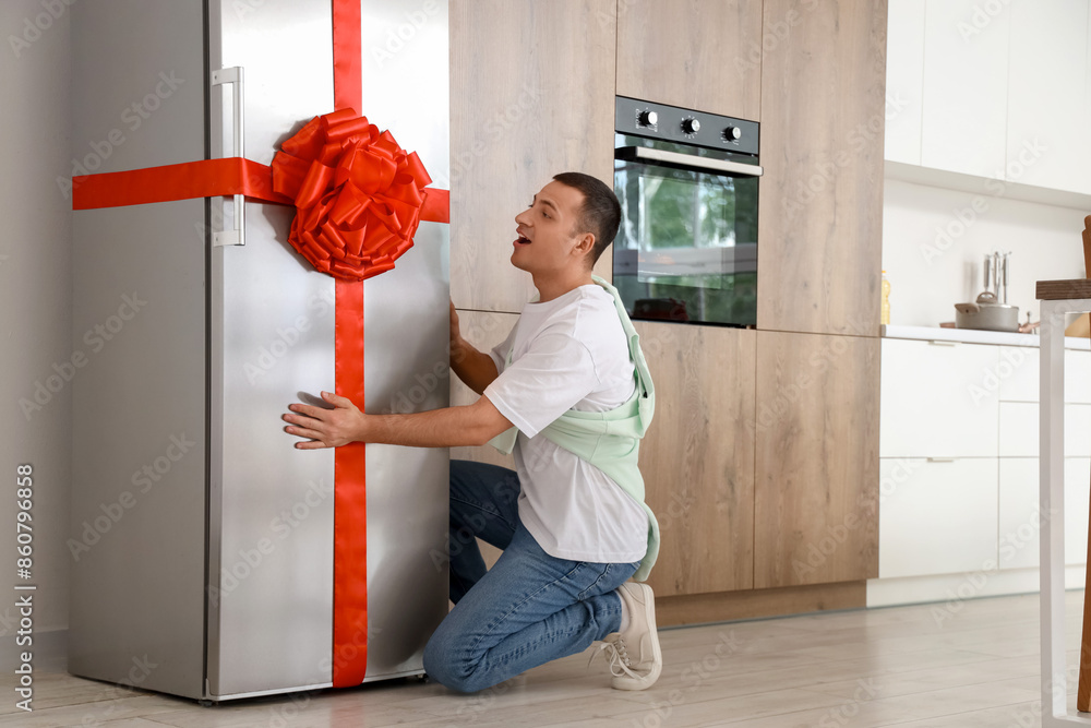 Sticker Young man with gift fridge in kitchen