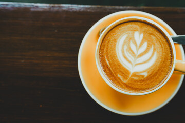 Hot coffee latte with latte art milk foam in cup mug on wood desk on top view. As breakfast In a coffee shop at the cafe,during business work concept,vintage style