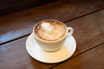 Hot coffee latte with latte art milk foam in cup mug on wood desk on top view. As breakfast In a coffee shop at the cafe,during business work concept,vintage style
